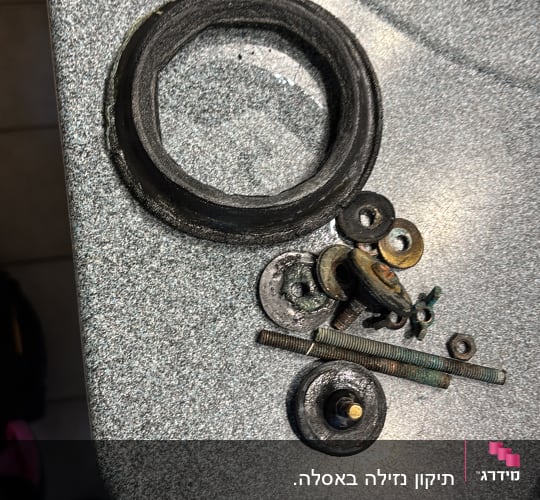 חלקי מתכת וגומי על משטח כיור, קשור לאינסטלציה